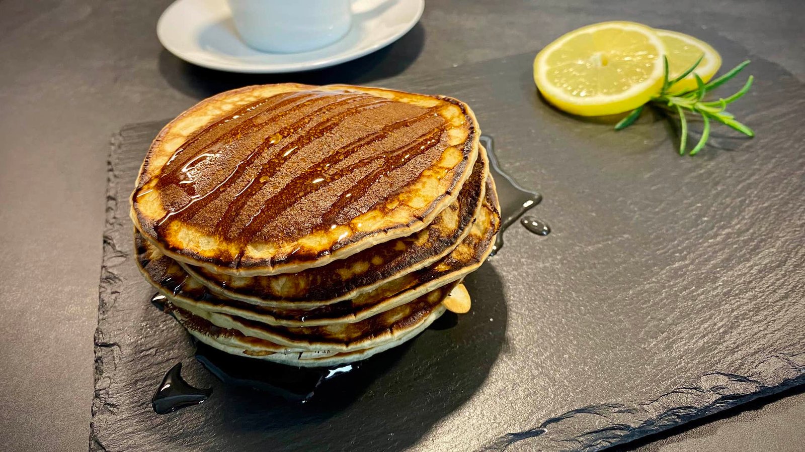 Ein Stapel fluffiger, goldbrauner amerikanischer Pancakes, die mit Ahornsirup übergossen sind, ist ein wahres Gaumenerlebnis zum Frühstück oder Brunch.