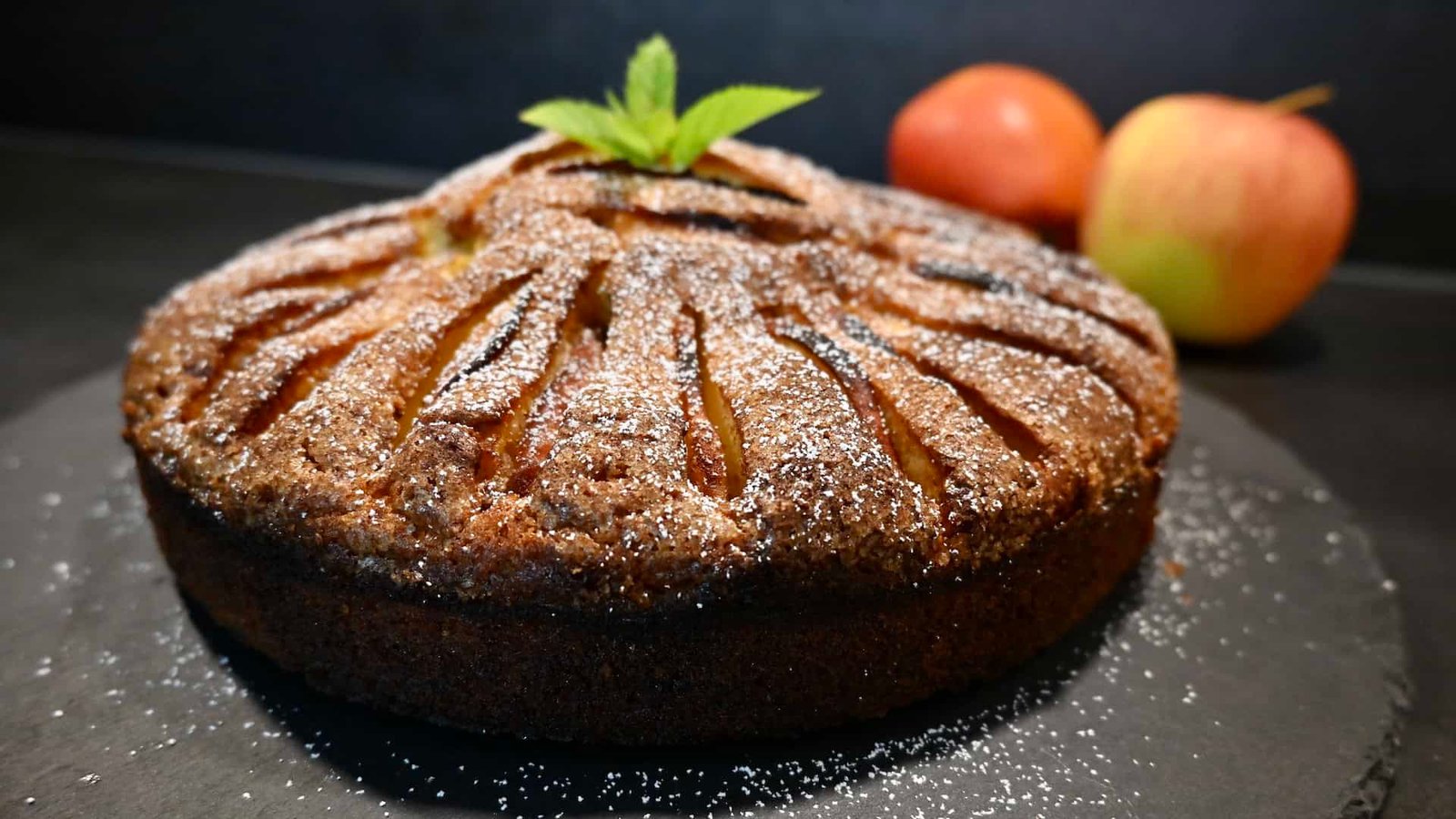 Ein frisch gebackener Apfelkuchen mit goldbrauner Kruste, dekoriert mit einer Prise Zimt und Zucker.