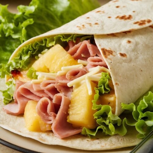 Ein Wrap Hawaii Art mit Ananas, Frischkäse, Salat und Schinken, angerichtet.