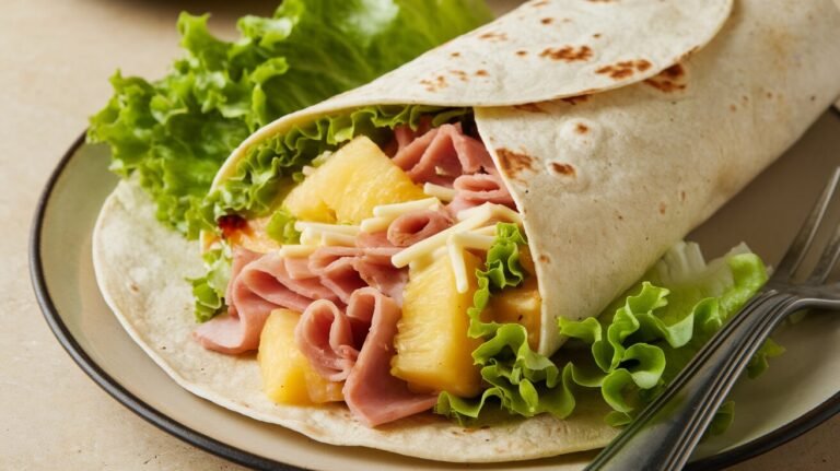 Ein Wrap Hawaii Art mit Ananas, Frischkäse, Salat und Schinken, angerichtet.