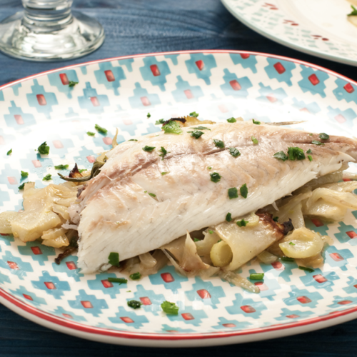 Ein Teller mit knusprig gebratenem Fisch, Fenchelkartoffeln und Kapern, serviert mit frischer Petersilie und Zitrone.