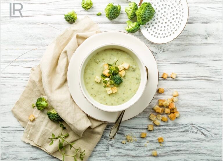 Eine cremige Brokkolisuppe, serviert mit knusprigen Croutons und frischen Kräutern auf einem rustikalen Holztisch.