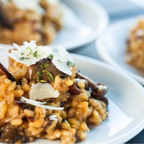 Cremiges Champignon-Gerstoni Risotto mit Pilzen, Parmesan und Thymian in einem Teller serviert.